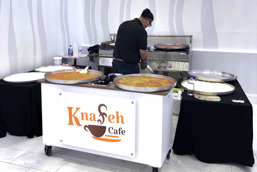 Live Knafeh catering show at an outdoor wedding with chef preparing fresh Knafeh at golden hour